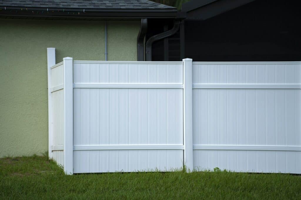 White vinyl picket fence on green lawn surrounding property grounds